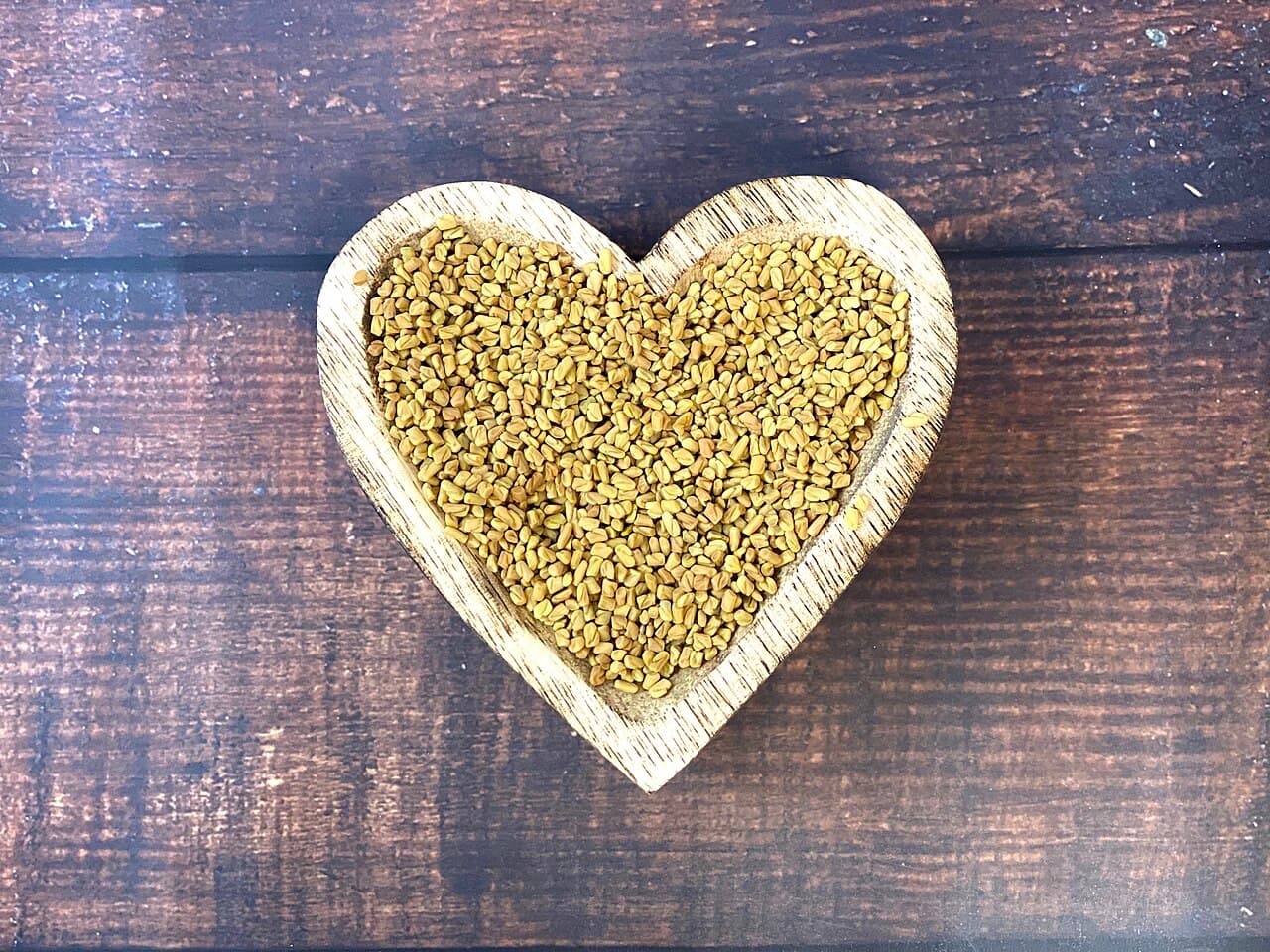 Methi (fenugreek) seeds in a heart-shaped wooden dish
