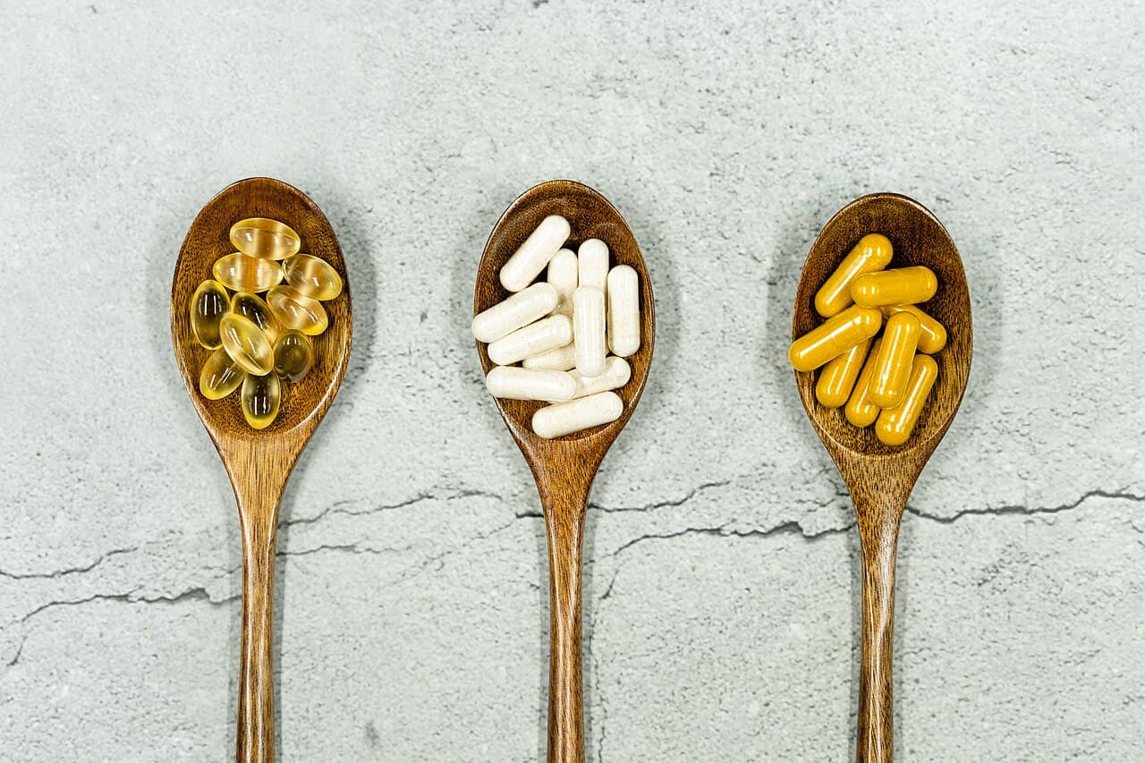 Herbal capsules and tablets on wooden spoons